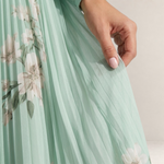 Valvet Oak House Mel midi dress in light green pleated chiffon with a delicate floral pattern and flowing silhouette.