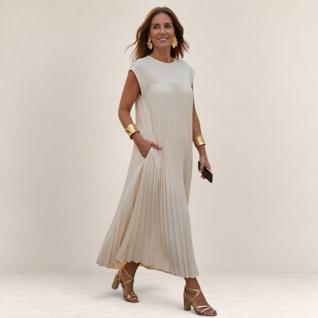 Valvet Oak House Chrysanthe cream pleated midi dress with cap sleeves worn by a woman with gold accessories
