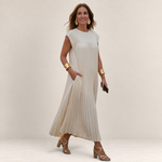Valvet Oak House Chrysanthe cream pleated midi dress with cap sleeves worn by a woman with gold accessories
