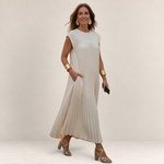 Valvet Oak House Chrysanthe cream pleated midi dress with cap sleeves worn by a woman with gold accessories