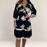 Valvet Oak House Hestia boho dress in black with white floral embroidery, featuring a V-neck and flared sleeves.
