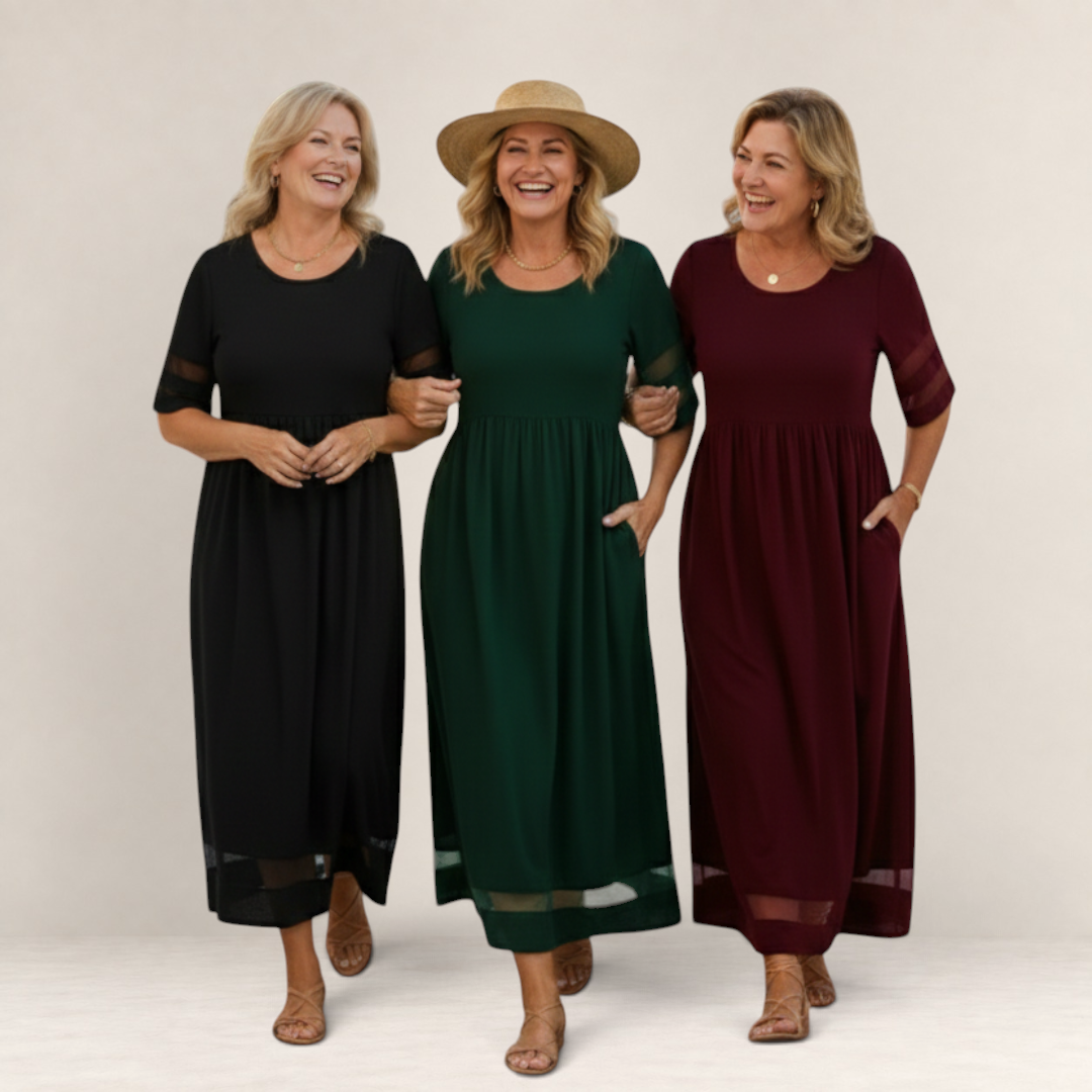 Three women wearing Valvet Oak House Penelope maxi dresses in black, forest green, and burgundy on a sunny street.