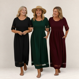 Three women wearing Valvet Oak House Penelope maxi dresses in black, forest green, and burgundy on a sunny street.
