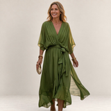 Valvet Oak House olive green flowy midi dress with V-neck and waist tie worn by a woman on a cobblestone street