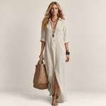 Valvet Oak House maxi shirt dress in beige linen with front buttons, worn by a model with a woven straw tote bag.