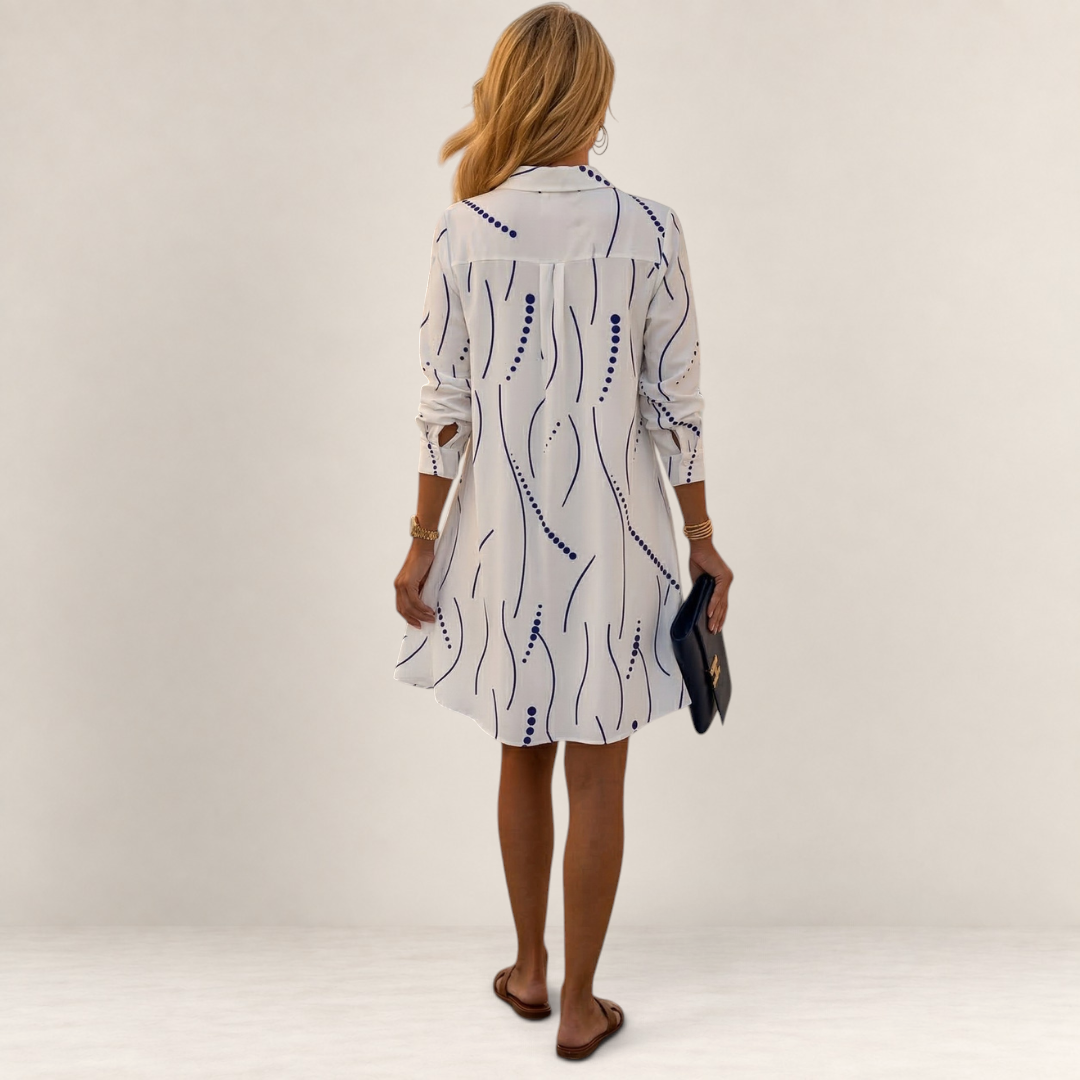 Back view of a woman wearing a Valvet Oak House white shirt dress with a blue wavy line pattern and A-line cut.