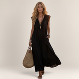 Valvet Oak House black linen-blend maxi dress with ruffles and pockets worn by a woman in a Mediterranean village