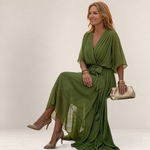 Valvet Oak House Helena olive green V-neck maxi dress with a belted waist worn by a woman on a Mediterranean street