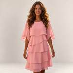 Valvet Oak House Cassandra pink layered dress with ruffled sleeves worn by a smiling woman in a studio setting