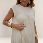 Valvet Oak House cream pleated midi dress with cap sleeves worn by a woman with gold statement jewelry