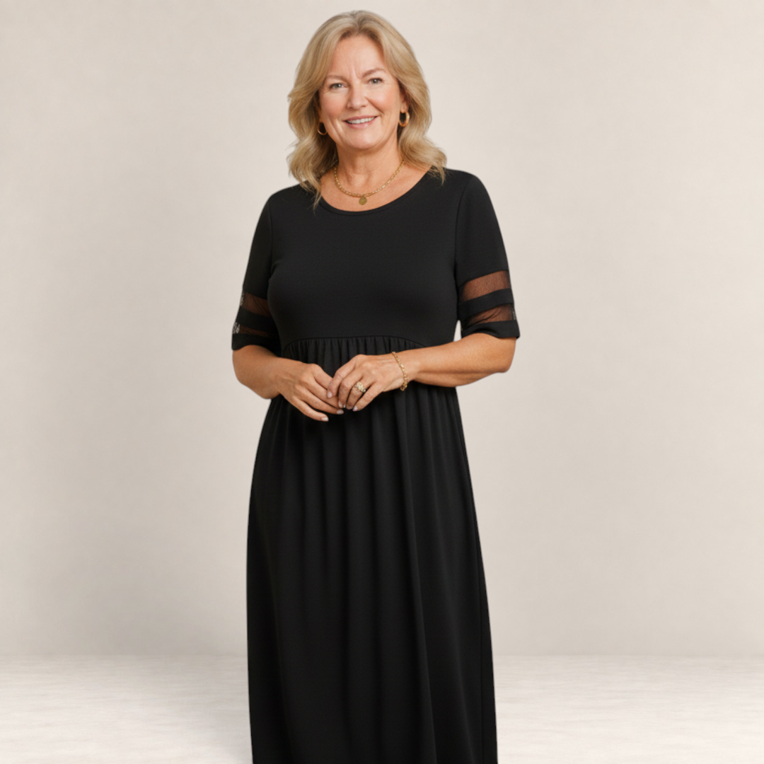 Valvet Oak House Penelope black maxi dress with sheer sleeve details worn by a smiling woman in a Mediterranean street