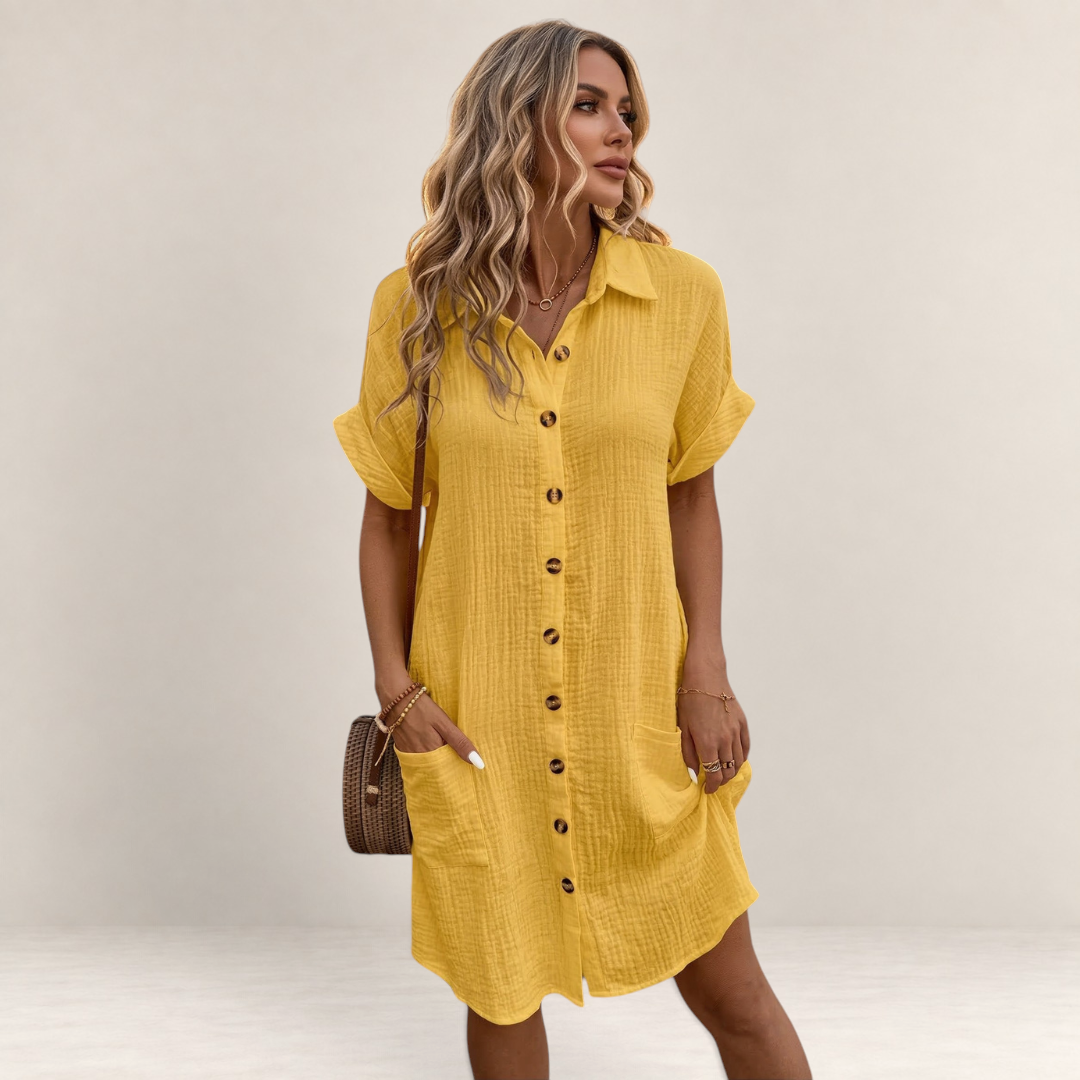 Valvet Oak House yellow button-down summer dress with ruffles and pockets worn by a woman on a cobblestone street