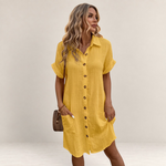 Valvet Oak House yellow button-down summer dress with ruffles and pockets worn by a woman on a cobblestone street