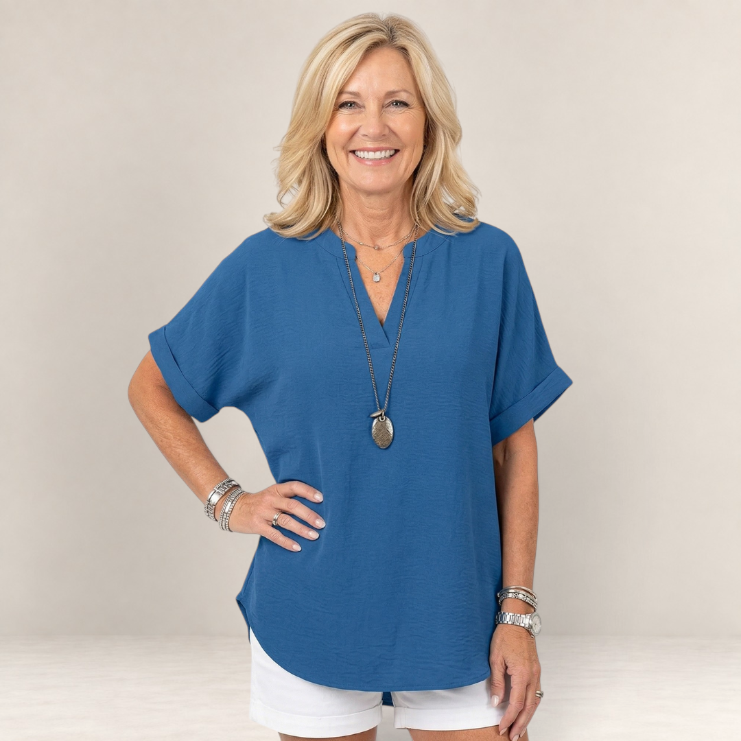 Valvet Oak House blue lightweight top with V-neck worn by a smiling woman with blonde hair against a white background