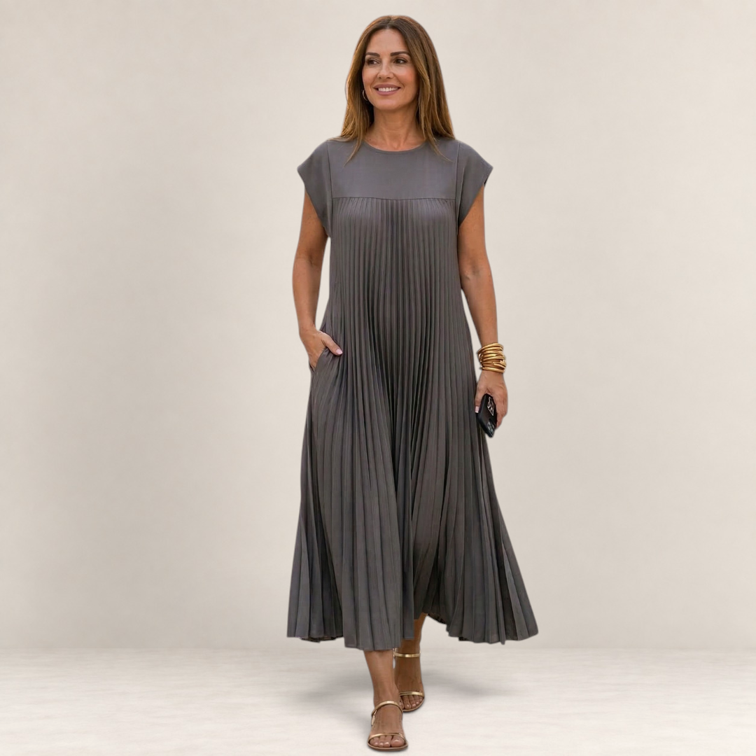 Valvet Oak House grey pleated midi dress with cap sleeves worn by a woman walking on a cobblestone street