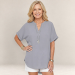 Valvet Oak House grey V-neck blouse with short sleeves worn by a smiling woman with blonde hair