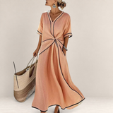 Valvet Oak House Mila peach midi dress with V-neck, waist knot detail, and black contrast trim on a model