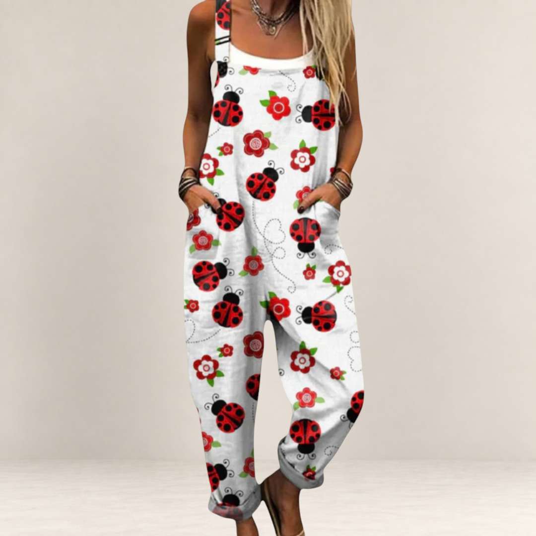 Valvet Oak House white jumpsuit with red ladybug and flower print, featuring a loose fit and adjustable straps.