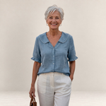 Valvet Oak House Pietra light blue cotton blouse with ruffled collar and sleeves worn by a smiling mature woman