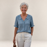 Valvet Oak House Pietra light blue cotton blouse with ruffled collar and sleeves worn by a smiling mature woman