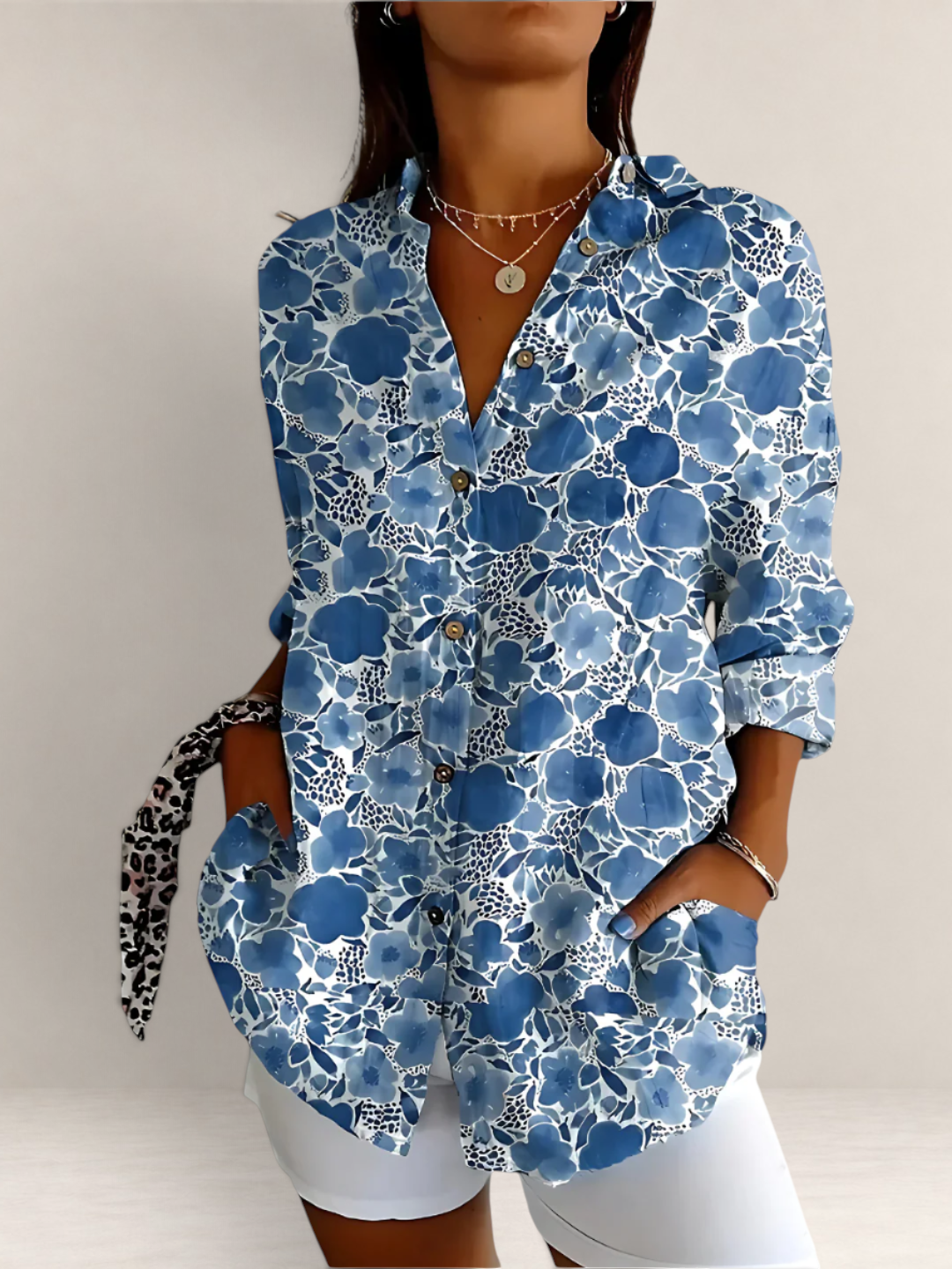 Valvet Oak House blue floral cotton blouse with V-neck and long sleeves worn with white trousers