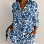 Valvet Oak House blue floral cotton blouse with V-neck and long sleeves worn with white trousers