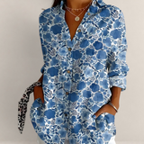 Valvet Oak House blue floral cotton blouse with V-neck and long sleeves worn with white trousers