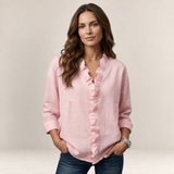 Valvet Oak House Elaine light pink linen blouse with ruffled V-neck worn by a woman with long wavy brown hair