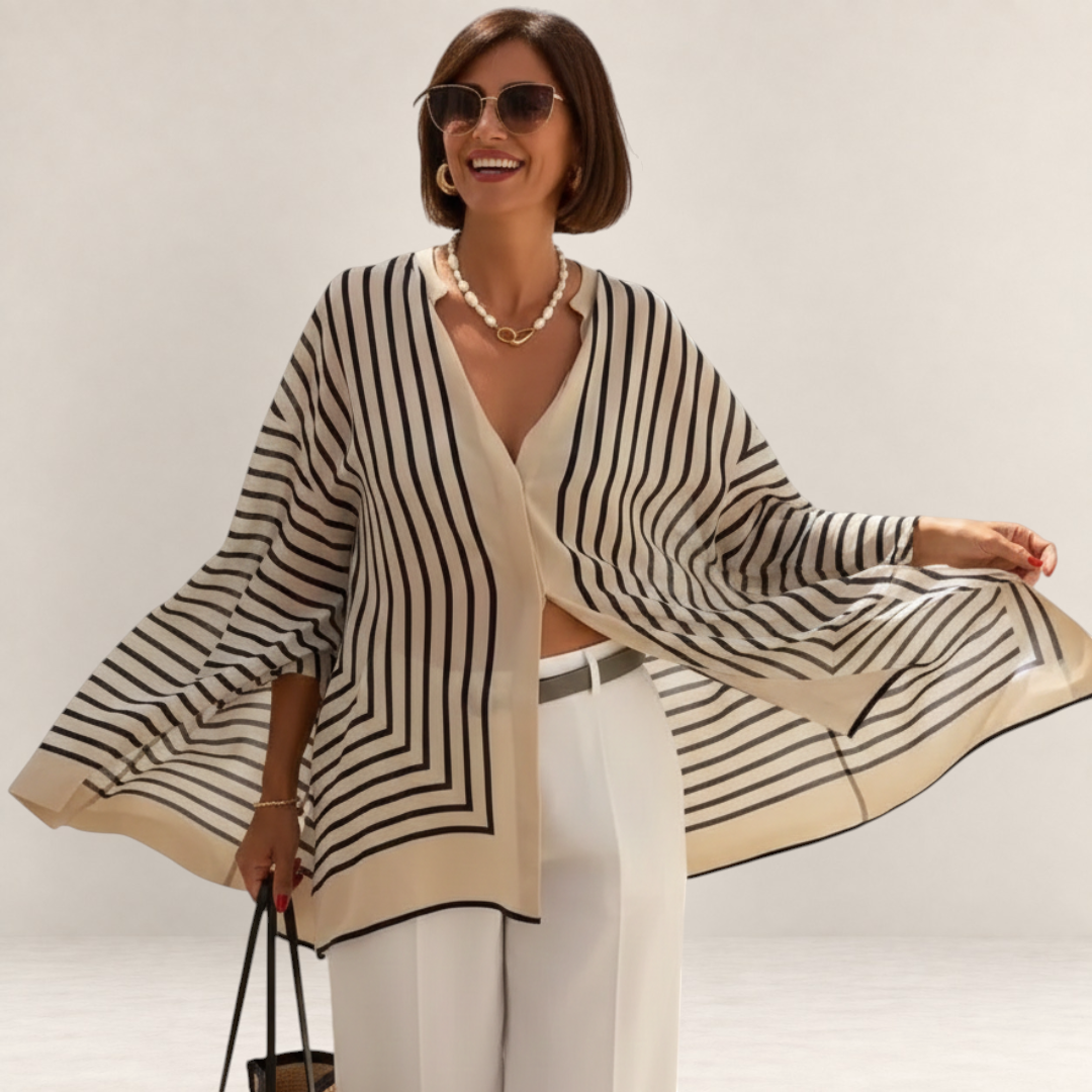 Valvet Oak House Thetis striped flowing blouse with V-neck worn by a smiling woman with sunglasses and pearl necklace