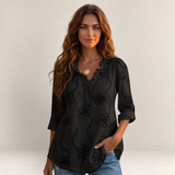 Valvet Oak House Larissa black blouse with floral embroidery and ruffled collar worn by a woman on a sunny street