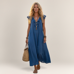 Valvet Oak House blue linen-blend maxi dress with ruffled neckline and side pockets worn by a blonde woman in Greece