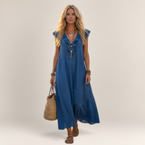 Valvet Oak House blue linen-blend maxi dress with ruffled neckline and side pockets worn by a blonde woman in Greece