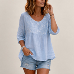 Valvet Oak House light blue blouse with delicate floral embroidery and patchwork details worn by a woman outdoors.