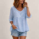 Valvet Oak House light blue blouse with delicate floral embroidery and patchwork details worn by a woman outdoors.