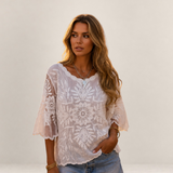 Valvet Oak House Melania white lace blouse with butterfly sleeves worn by a woman on a cobblestone street at sunset