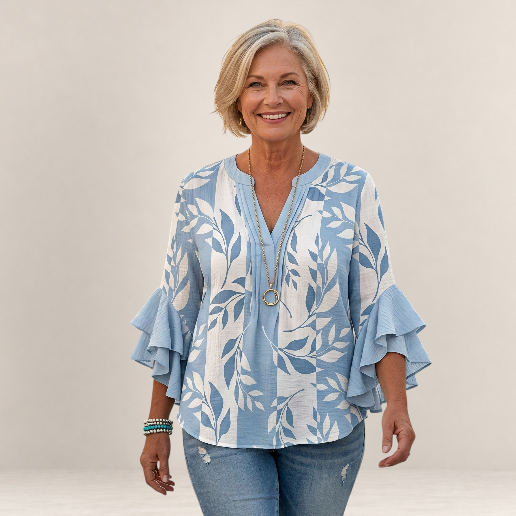 Valvet Oak House Agapi blouse with blue and white leaf print, V-neck, and ruffled sleeves worn by a smiling woman.
