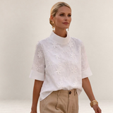 Valvet Oak House Calíope white blouse with floral relief embroidery, high neck, and short sleeves on a model