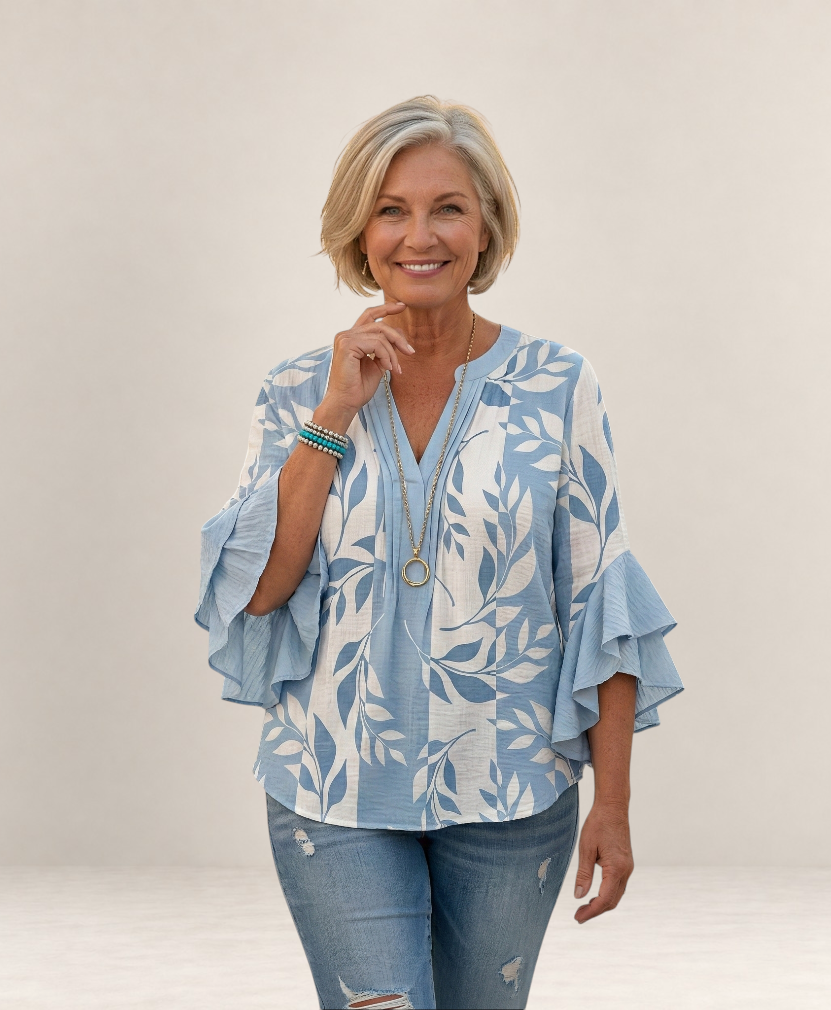 Valvet Oak House Agapi blouse with blue and white leaf print, V-neck, and ruffled sleeves worn by a smiling woman.