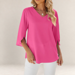 Valvet Oak House pink V-neck blouse with 3/4 sleeves and flared cuffs worn by a woman with white trousers