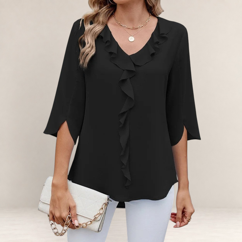 Valvet Oak House black blouse with ruffled neckline and 3/4 sleeves worn with white trousers and a clutch bag