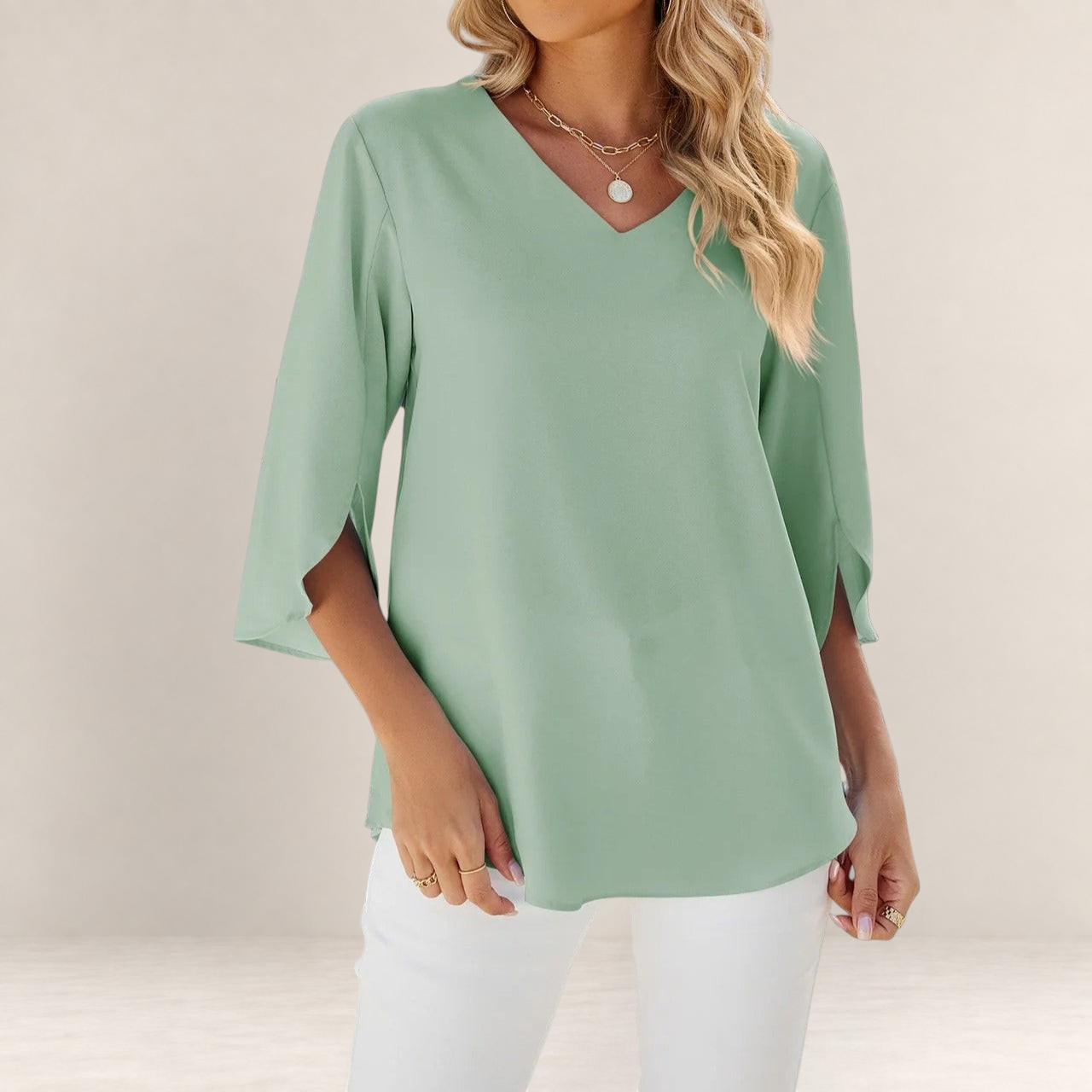 Valvet Oak House sage green blouse with V-neck and 3/4 sleeves, styled with white trousers for an elegant look.