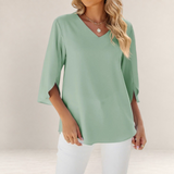 Valvet Oak House sage green blouse with V-neck and 3/4 sleeves, styled with white trousers for an elegant look.
