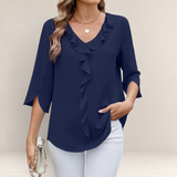 Valvet Oak House navy blue blouse with ruffled neckline and 3/4 sleeves worn with white trousers