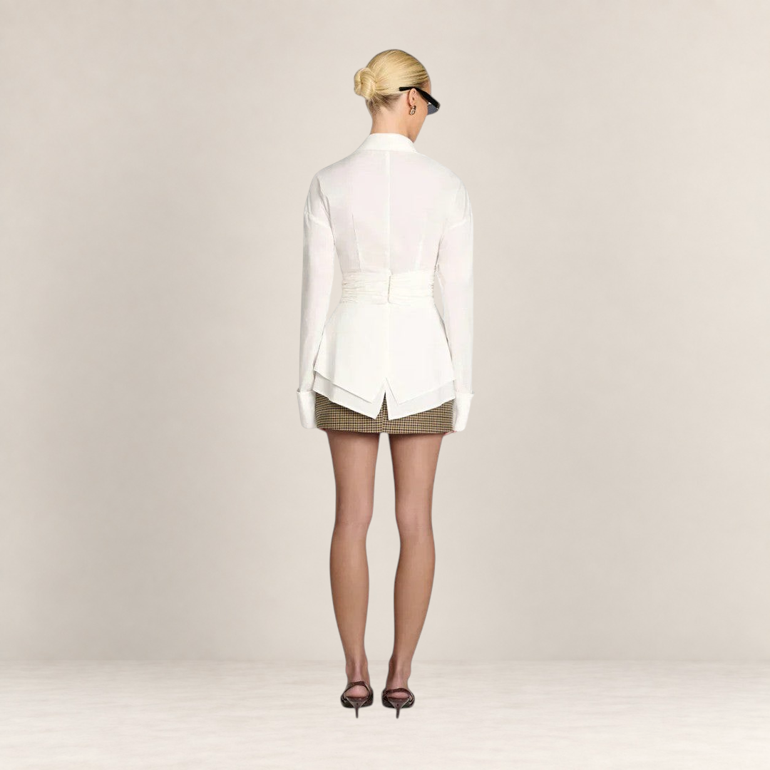 Back view of a woman wearing a white Valvet Oak House Teofánie lace blouse with oversized cuffs and a cinched waist.