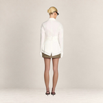 Back view of a woman wearing a white Valvet Oak House Teofánie lace blouse with oversized cuffs and a cinched waist.