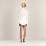 Back view of a woman wearing a white Valvet Oak House Teofánie lace blouse with oversized cuffs and a cinched waist.