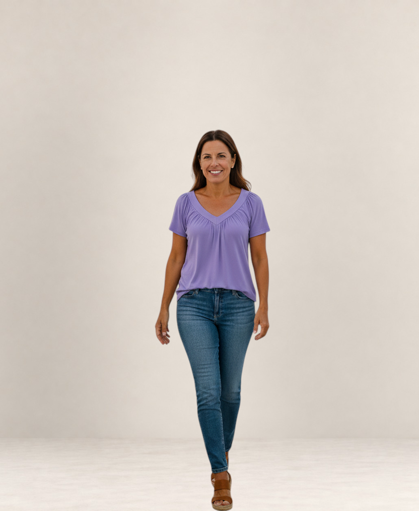 Valvet Oak House Despina lavender blouse with V-neck and pleated details worn by a smiling woman with blue jeans